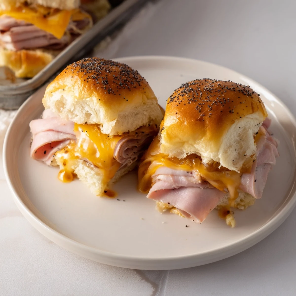 Golden-brown Budget-Friendly Ham & Cheese Sliders, oozing melted cheese between soft, toasted buns, are ready to eat.