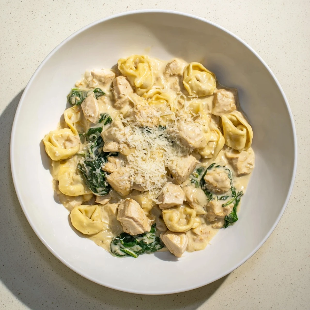 Steaming bowl of Creamy Chicken and Spinach Tortellini, rich with Parmesan cheese and herbs.