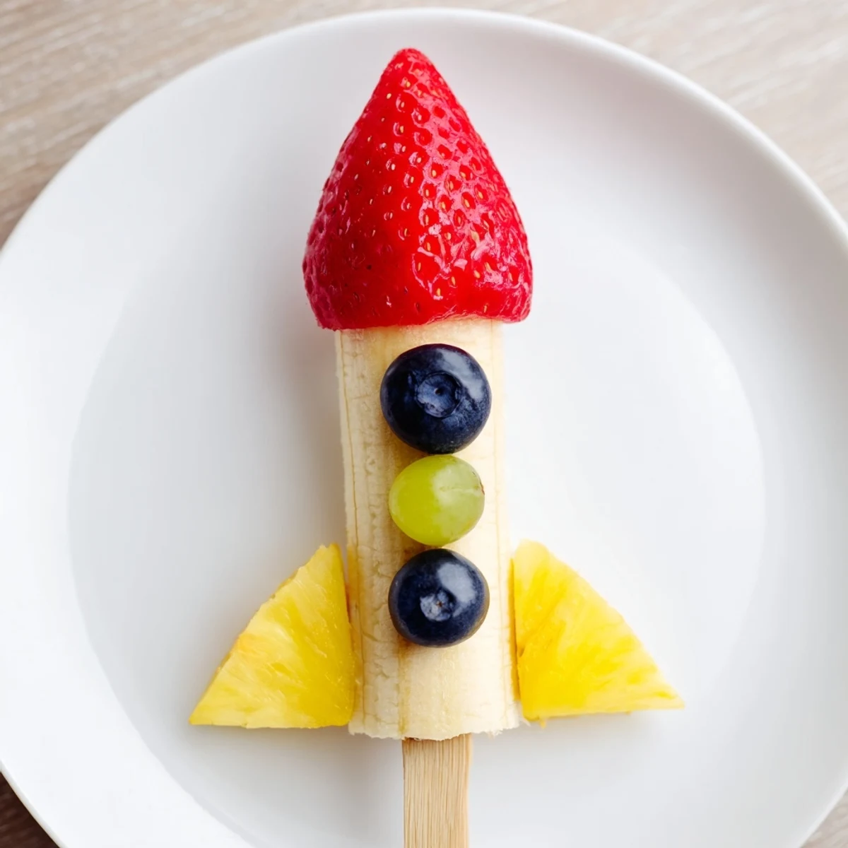 These colorful Rocket Ship Fruit Skewers feature pineapple flames and grape bodies, a playful snack.