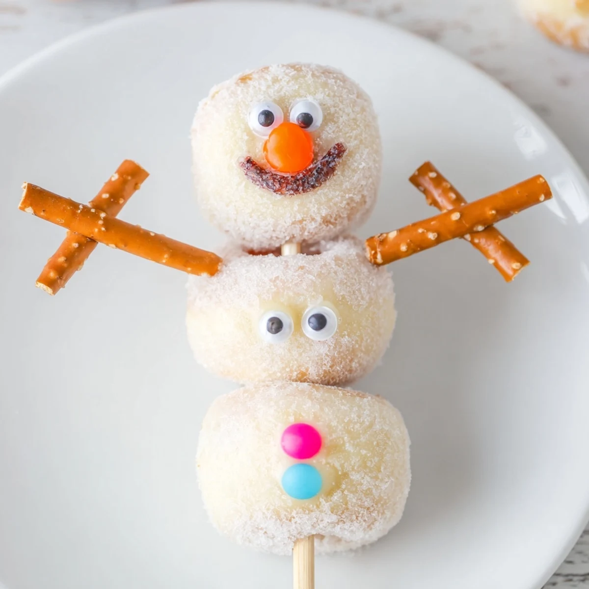 Delicious, stack of mini donut snowmen with chocolate chip mouths, ready for a winter treat.