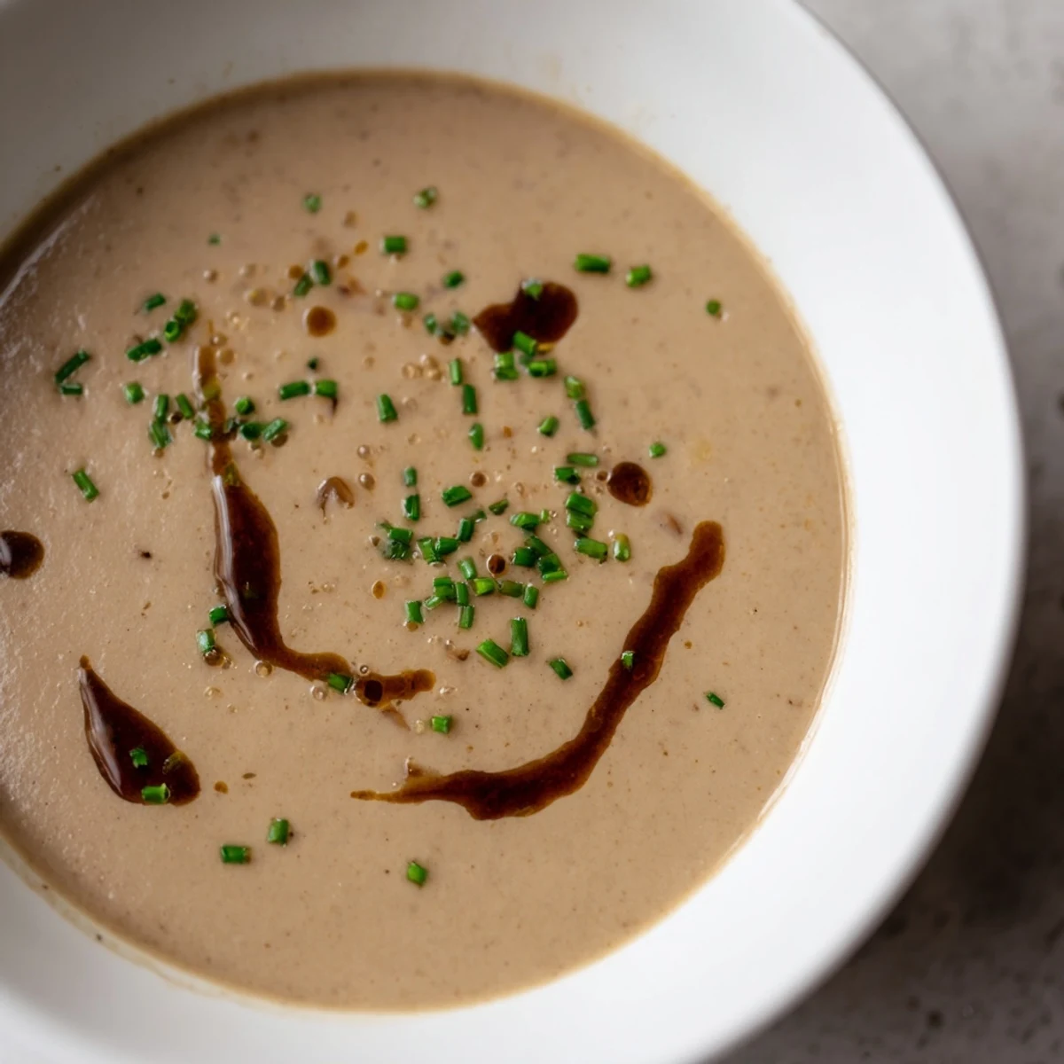 Close up shot of golden-hued Mushroom Bisque with visible mushroom pieces, ready to serve.
