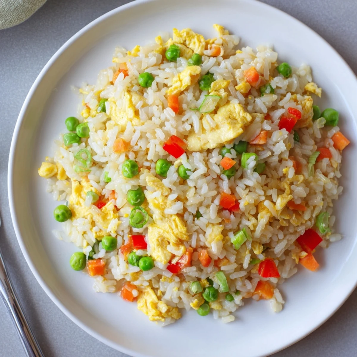 Vibrant Egg Fried Rice in a skillet, featuring golden scrambled eggs, crisp bell peppers, and tender peas tossed in savory soy sauce and sesame oil.