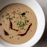 Close up shot of golden-hued Mushroom Bisque with visible mushroom pieces, ready to serve.