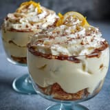 Creamy limoncello tiramisu cups layered with lemon-soaked ladyfingers and mascarpone cream, garnished with fresh zest and white chocolate curls.