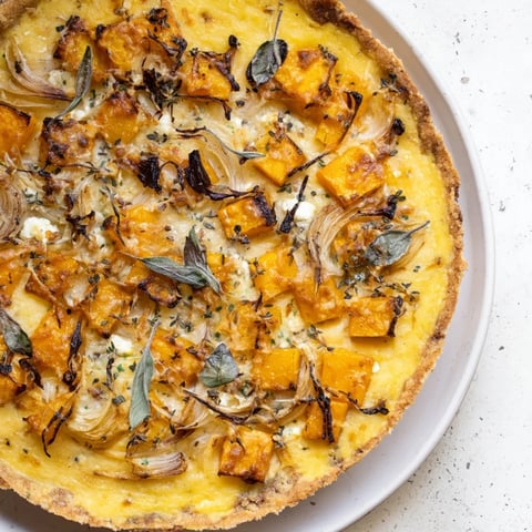 Golden-brown potato crust quiche filled with roasted squash and herbs, perfect for brunch.