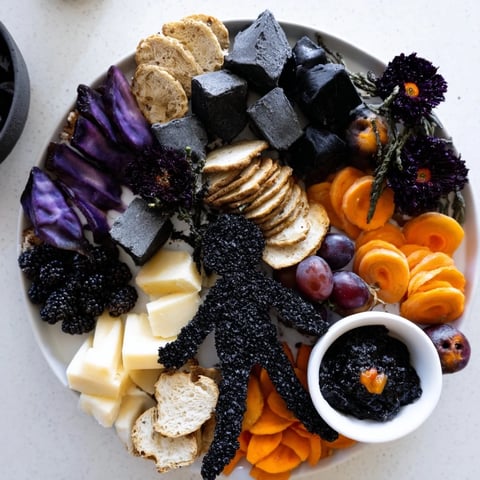 Spooky Ghostly Outline Halloween Charcuterie Board overflowing with cheese, fruits, and savory bits, ready to eat.