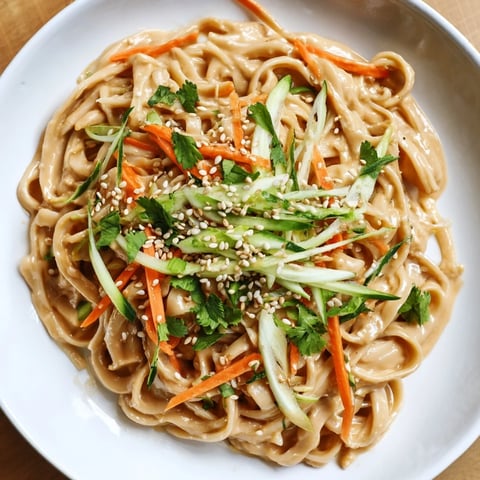 Silky cold sesame noodles tossed with crisp carrots and cucumber, ready to slurp and enjoy.