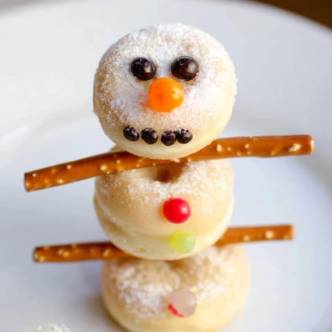 Homemade mini donut snowman skewers, a festive dessert with pretzel arms, great for kids.