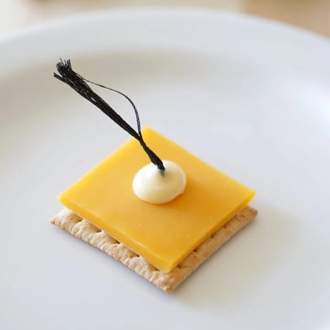 The Graduation Cap Snack, a fun, easy appetizer featuring cheese squares and fruit tassels.