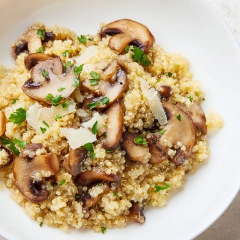A close-up shot of the earthy Mushroom Quinoa Risotto, garnished with fresh parsley, looks delicious.