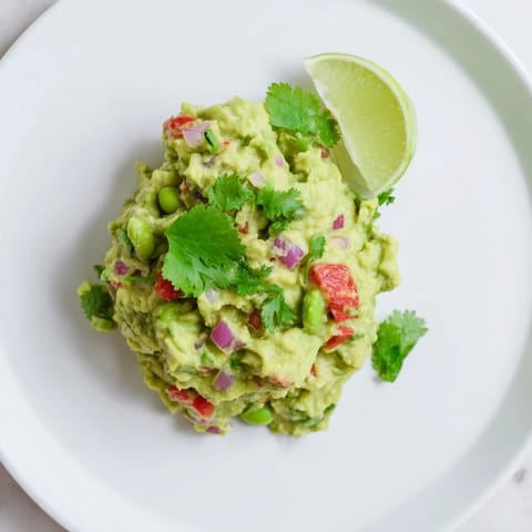 A close-up of creamy Edamame Guacamole: a vibrant, flavorful appetizer bursting with fresh ingredients.