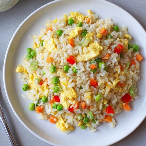 Vibrant Egg Fried Rice in a skillet, featuring golden scrambled eggs, crisp bell peppers, and tender peas tossed in savory soy sauce and sesame oil.
