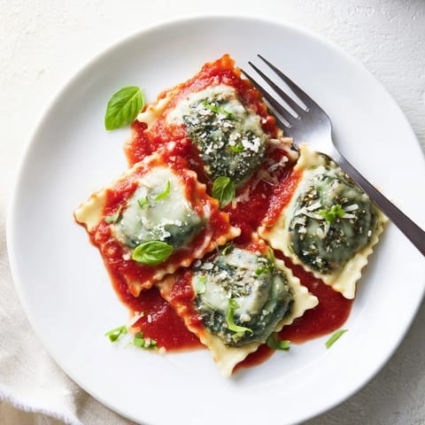 Tender Spinach Ricotta Ravioli served on a white plate with a sprinkle of Parmesan cheese.
