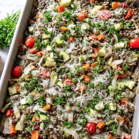 Hearty vegetarian Green Lentil and Vegetable Casserole topped with bubbly cheese and vibrant diced vegetables, fresh from the oven.