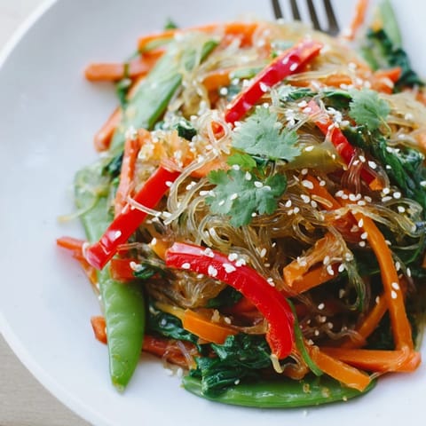 Healthy, low-calorie vegan kelp noodle stir-fry served hot with lime wedges, fresh cilantro, and julienned carrots for a crunchy finish.  