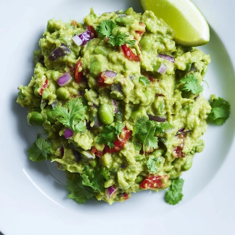 Freshly made Edamame Guacamole, easily imagined, with bright cilantro and lime wedges on the side.