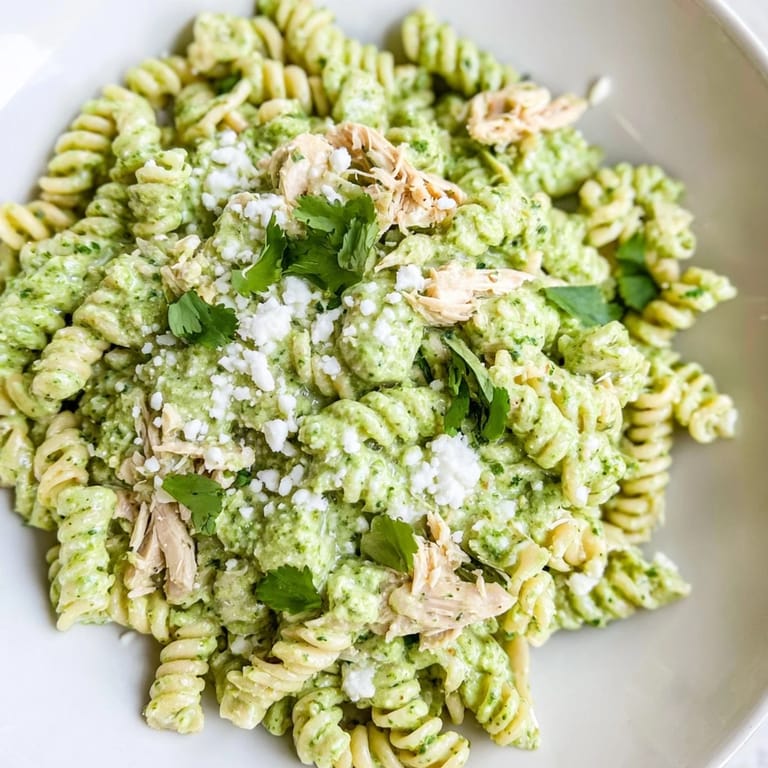 A vibrant serving of Cilantro Lime Chicken Pasta tossed with rotini, fresh cilantro, and creamy yogurt sauce, topped with feta and lime.