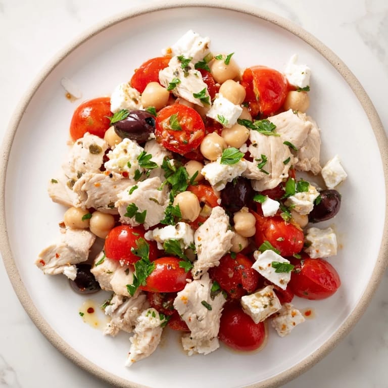 Serving suggestion for Mediterranean Chickpea Chicken Salad featuring tender chickpeas and red onion slices, tossed in a zesty lemon-oregano dressing beside warm pita bread.