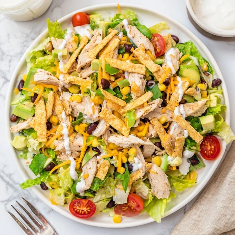 A freshly tossed serving of Crunchy Taco Chicken Salad drizzled with creamy lime dressing and extra crunch.