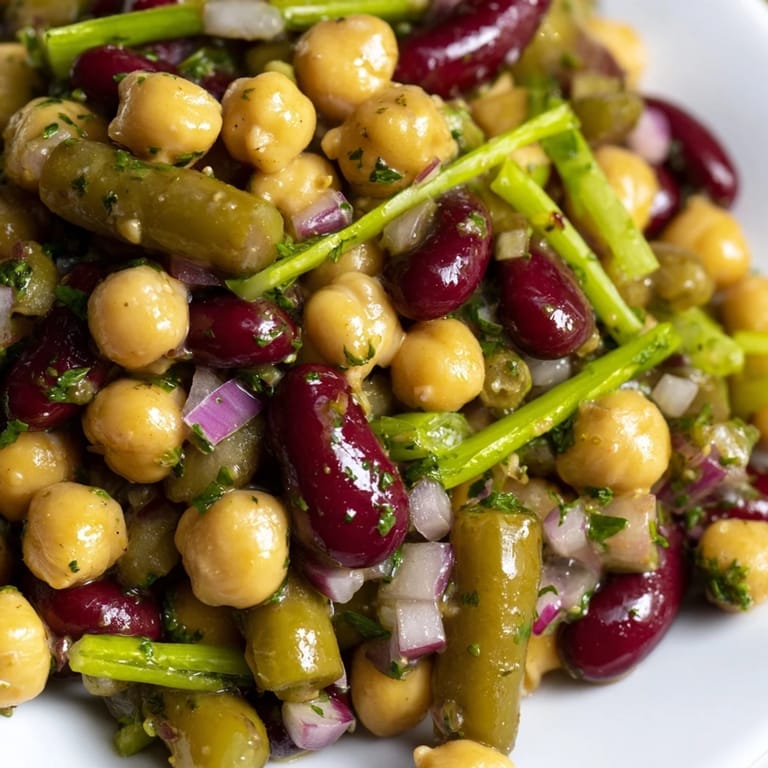 Freshly tossed Three-Bean Salad garnished with crisp celery, red onion, and parsley, ready for a summer picnic.  